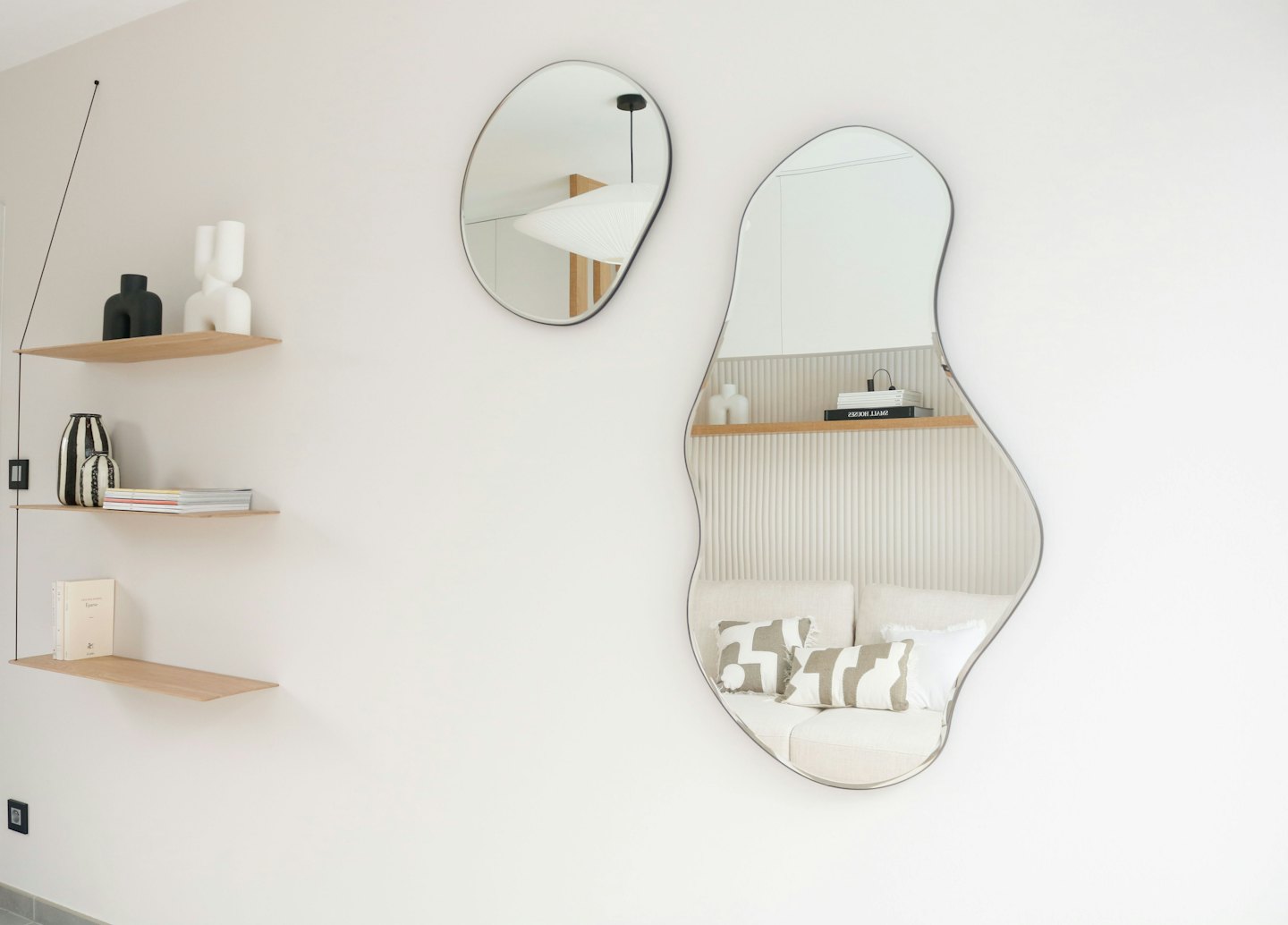 Minimalistische Wanddeko mit schwebenden Regalen und organischen Spiegeln.